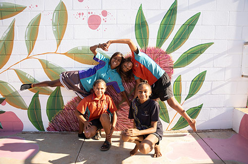 Group of young people posing in front of a mural